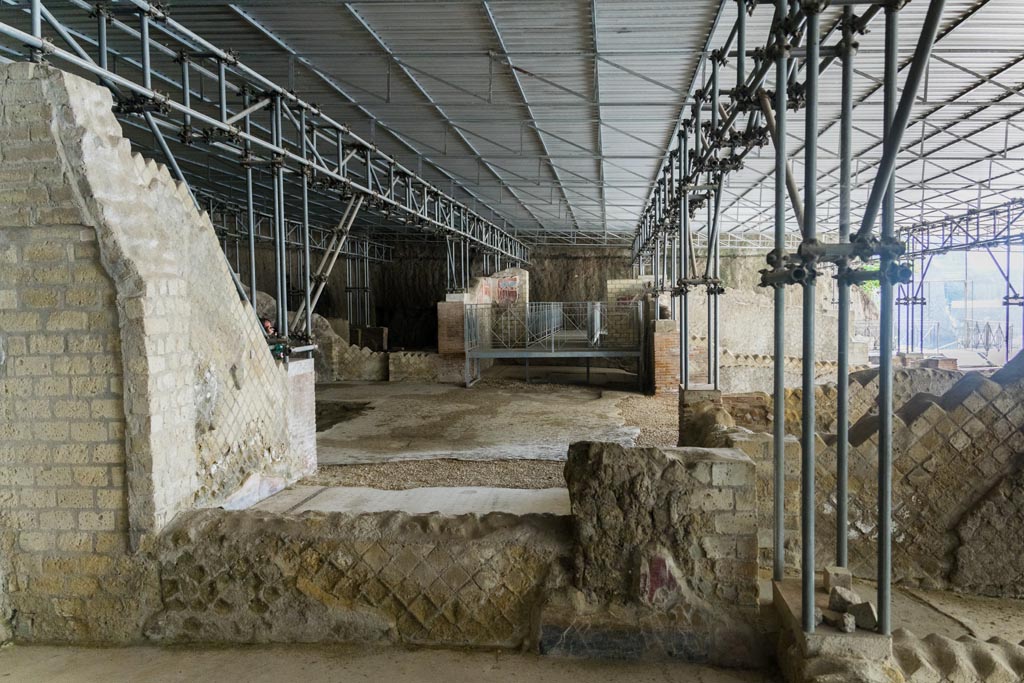 Herculaneum Villa dei Papiri. October 2023. Looking towards east wall of room (r), at the rear of room (s), on right.
Ahead is the area of room (d) the west ala, and atrium (c), looking towards the room (e), the east, with painted remains in north-east corner.
Photo courtesy of Johannes Eber.